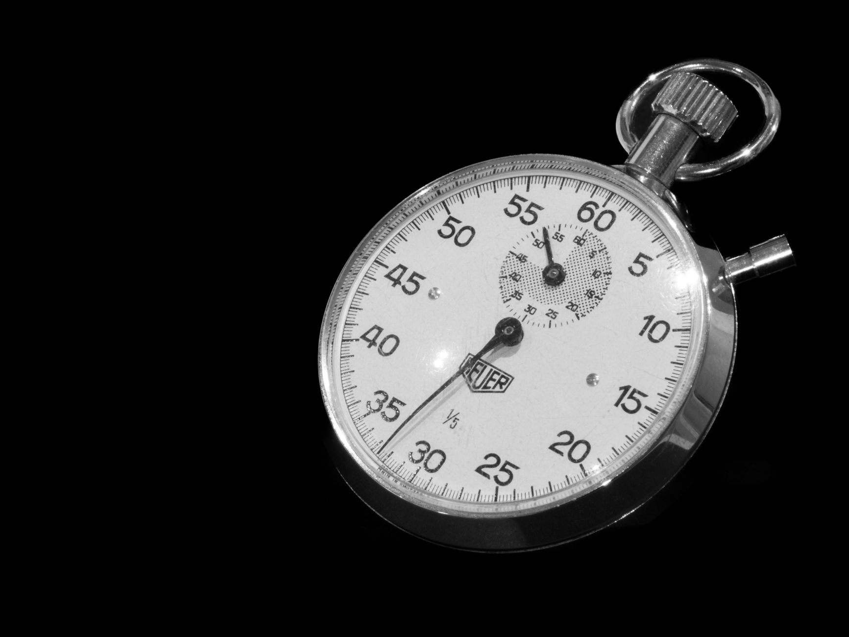 Vintage mechanical stopwatch with black dial against a dark background